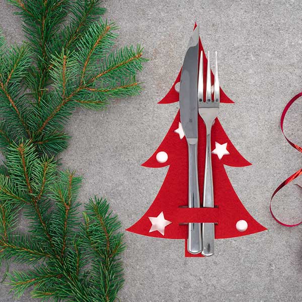 Roter Besteckhalter in Weihnachtsbaumform auf einer festlichen Weihnachtstafel